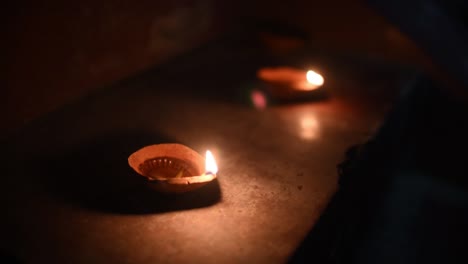 two lighted diyas on stairs for celebration of diwali or christmas at night, flames reflecting on floor