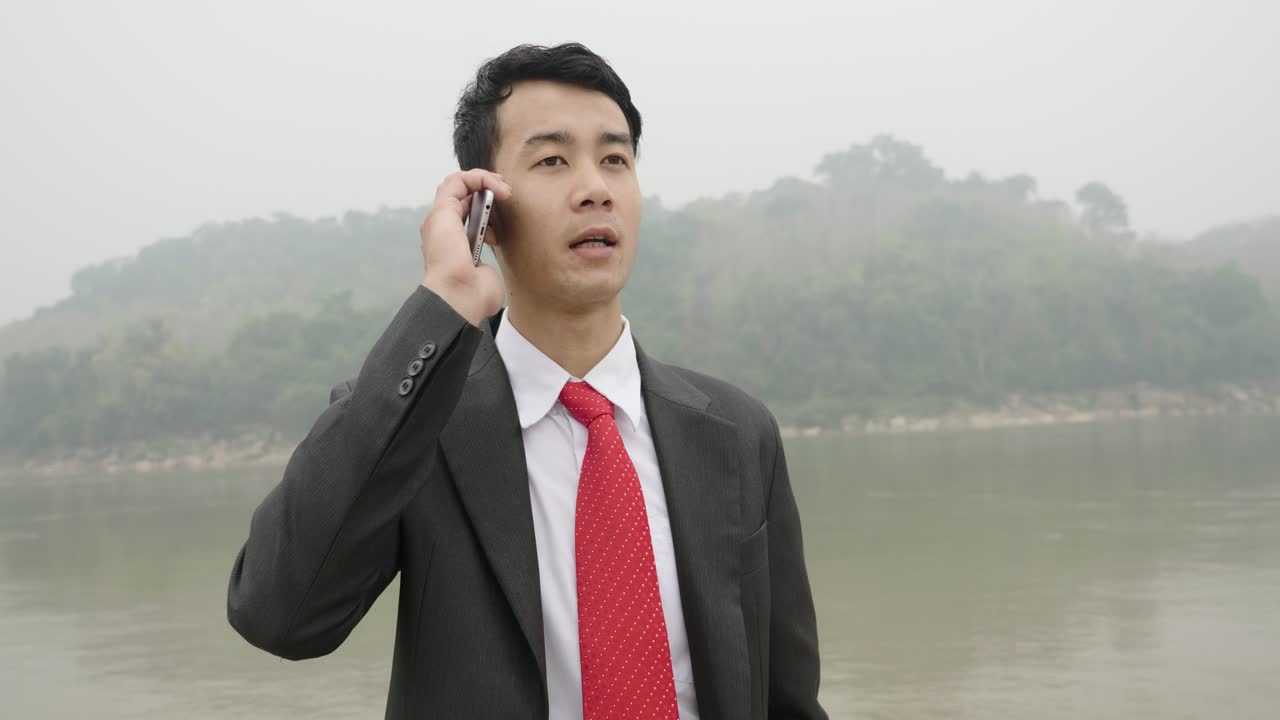 Businessman Talking on Phone by the River