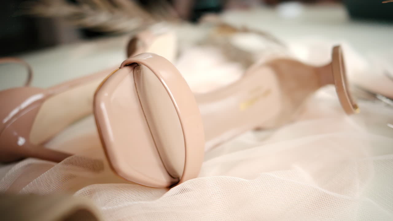 A beige pair of strappy heels on a piece of tulle