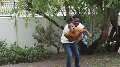 African-American-father-gives-piggyback-ride-to-son-outdoors