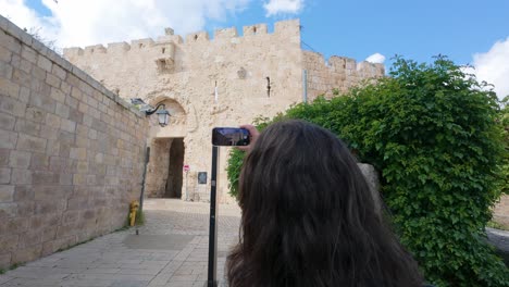 woman taking photos with her smartphone at the zion gate in the old city of jerusalem. slow motion.