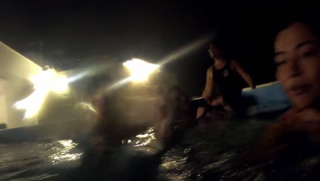 amigos de la fiesta cantando y bailando en la piscina por la noche en una terraza de la casa de la playa bebiendo cerveza