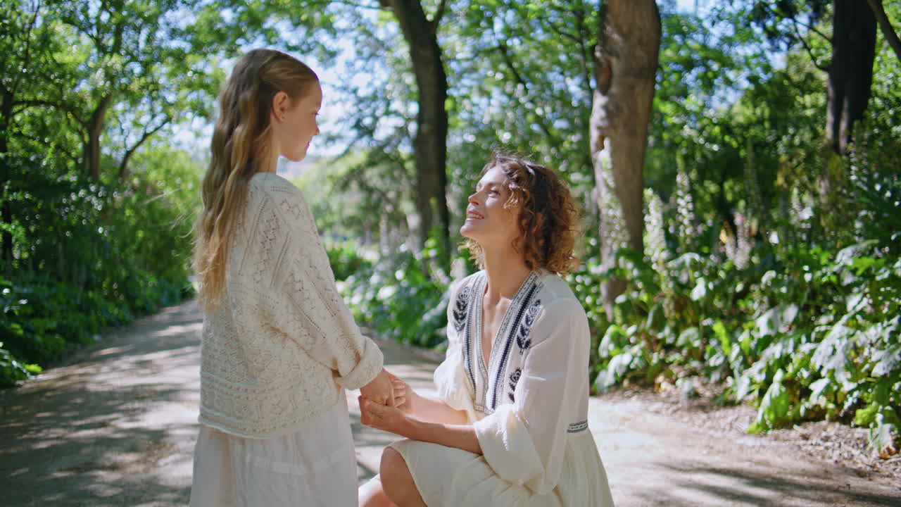 Mother daughter communicating sunshine park standing on greenery alley closeup