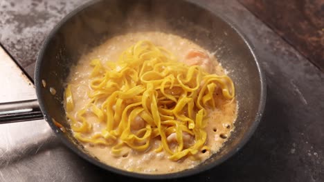 cooking tagliatelle with creamy sauce and shrimp