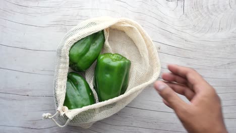 recoger a mano un capsicum verde de una bolsa de compras ,