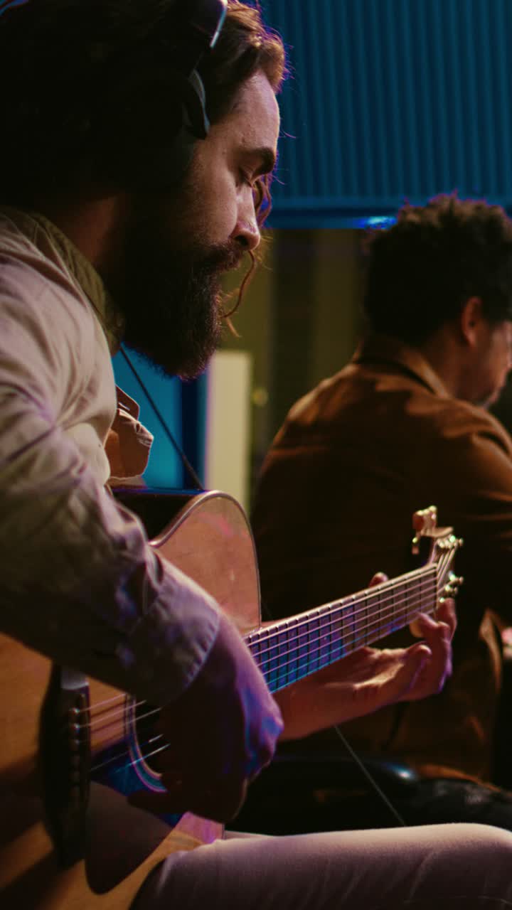 Músico tocando la guitarra acústica en un estudio de grabación profesional