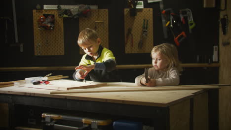 static view of blonde kids learning practical skills in garage.