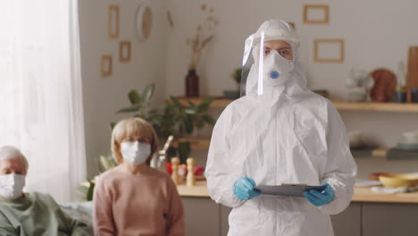 doctor in protective uniform at home of senior patients