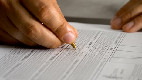 de cerca en la mano del estudiante llenando la prueba de opción múltiple