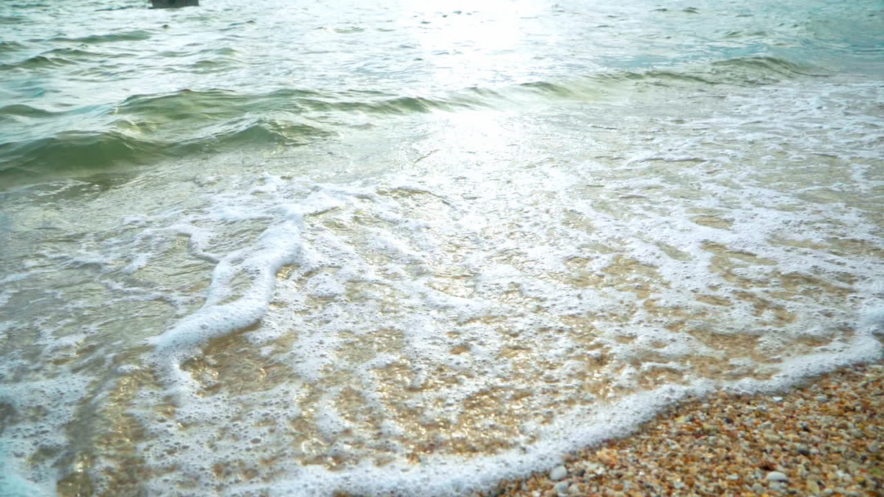 해가 지는 동안 열대 지방의  ⁇  모래 해변의 해안에 도달하는 파도와 함께 아름다운 해변