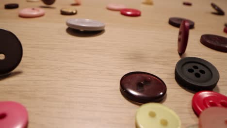 closeup of different colorful sewing buttons falling on a wooden table. fashion concept