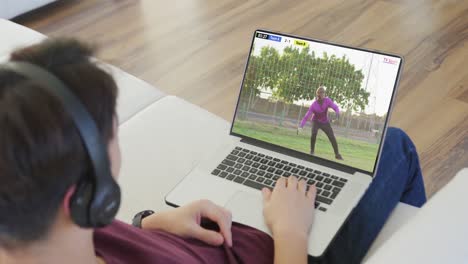 video de una persona sentada en el sofá y viendo un partido de fútbol en una computadora portátil