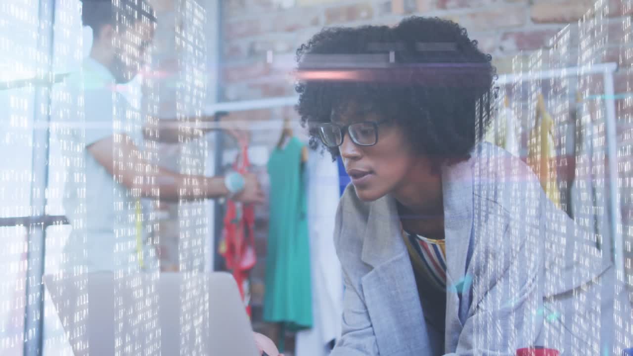 pantallas con procesamiento de datos contra diseñadora de moda afroamericana hablando en teléfono inteligente