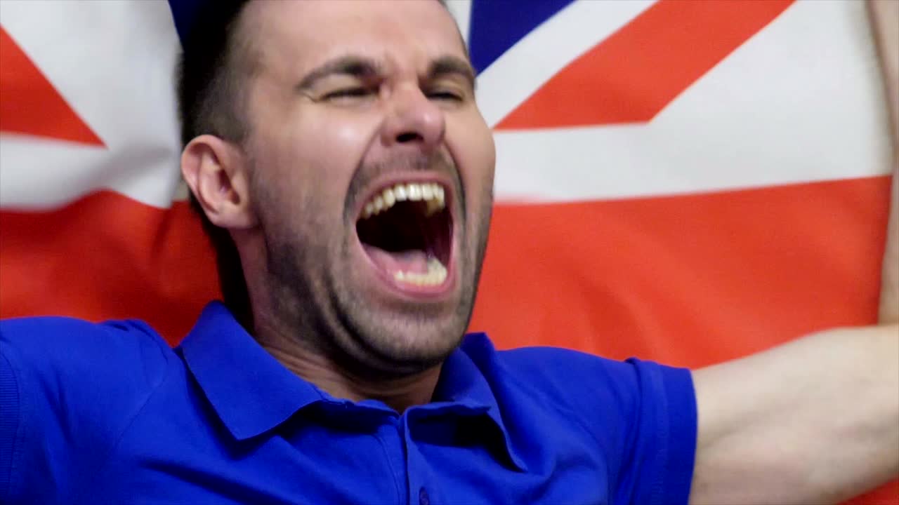 fanático británico celebrando mientras sostiene la bandera británica en cámara lenta, 4k, de alta calidad