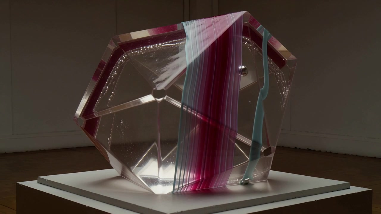 Panning camera revealing faceted sculpture on plinth, exposing pink band and bubbles for display
