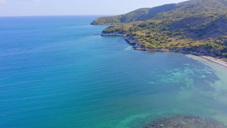 Aerial-drone-shot-of-coral-reef-under-transparent-water-and-sandy-beach-of-Monte-Rio-in-Azua-during-summer---Scenic-Landscape-on-Dominican-Republic-Island