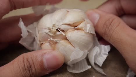 hands peeling cloves of garlic over a kitchen counter, preparing ingredients for cooking in a cozy kitchen setup