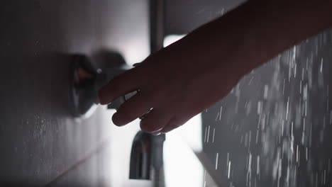 woman unscrews water in shower to pressure to wash. gentle hand of woman turns on shiny tap in shower to wash body. hand of lady unscrew hot water