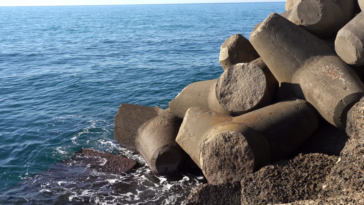 Amazing water splashing against sea shore, massive defensive constructions at the beach for preventing water flood. Sea pier fortification with powerful stone blocks of triangular shape