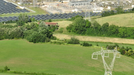 high-voltage power lines and solar farm in a lush green field on a sunny day