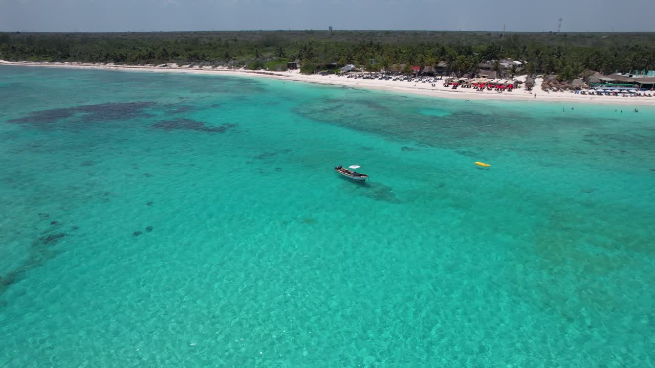 anclaje de barco en una playa tropical en aguas azules claras del océano con árboles en el fondo- retiro aéreo