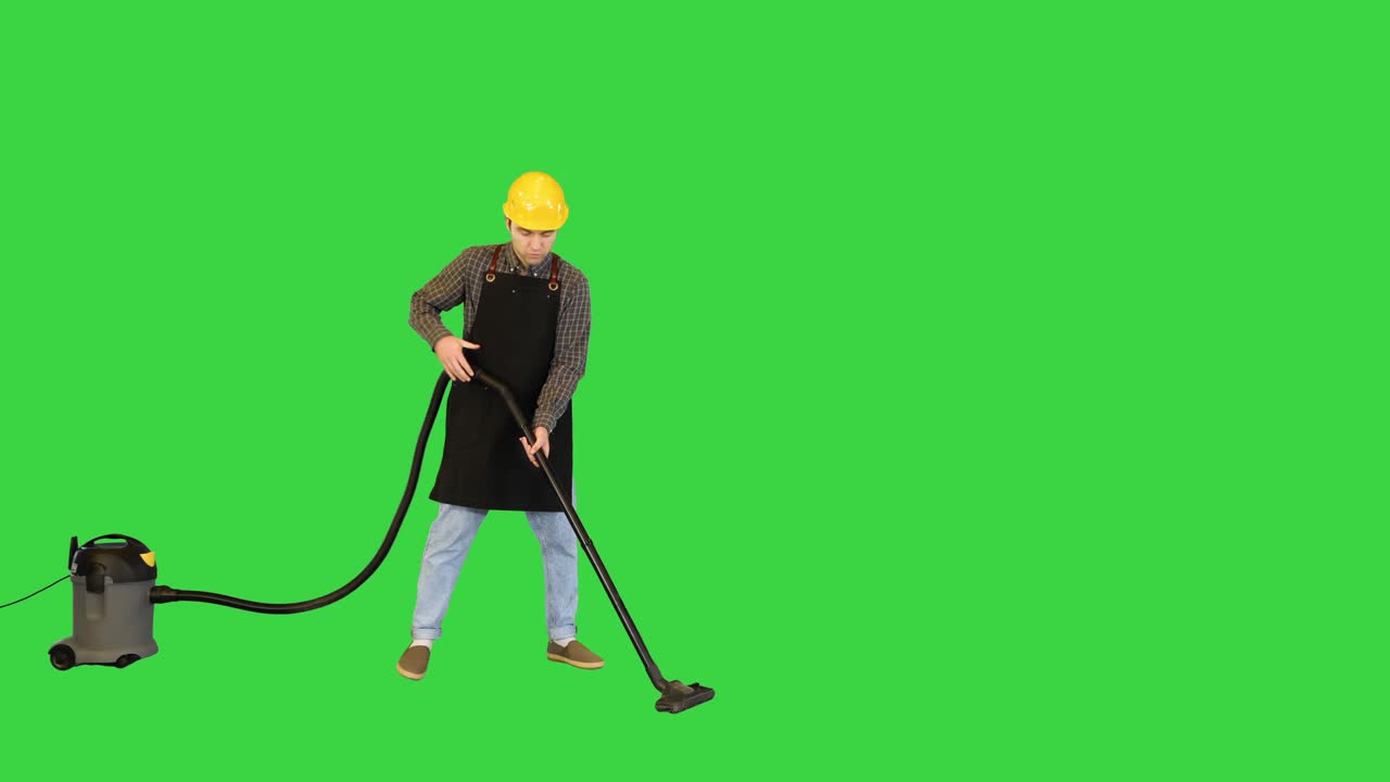 trabajador en un casco aspirando el piso en una pantalla verde, llave cromada