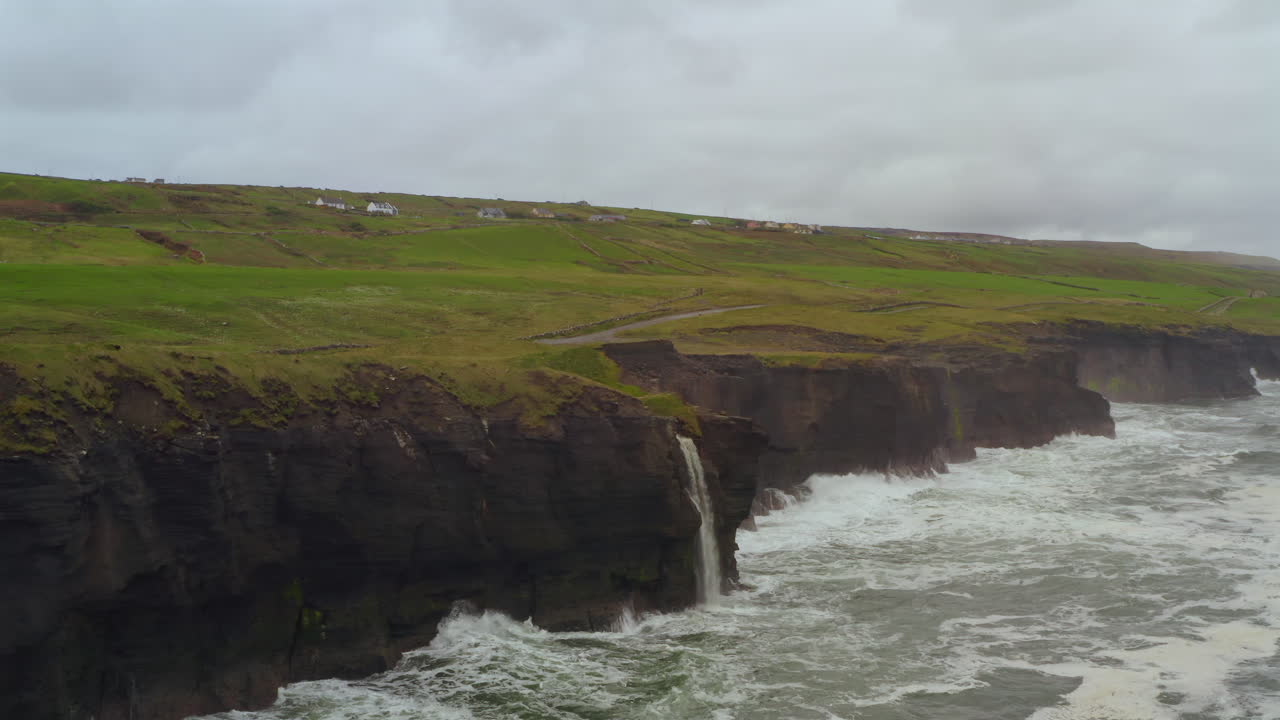 Smooth orbital aerial of Cliffs of Moher at Doolin with prominent waterfall cascade. Ireland