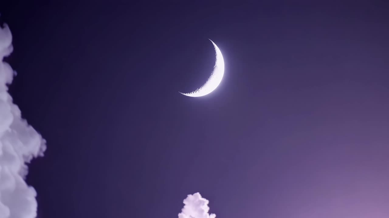A serene night sky video with a crescent moon and fluffy clouds, captured from a low angle