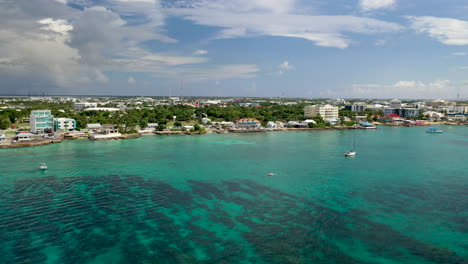 drone shot over the ocean moving towards small cayman islands town