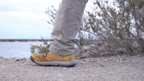 slow motion close-up shot of a man walking along a gravel path at the sete salt flats