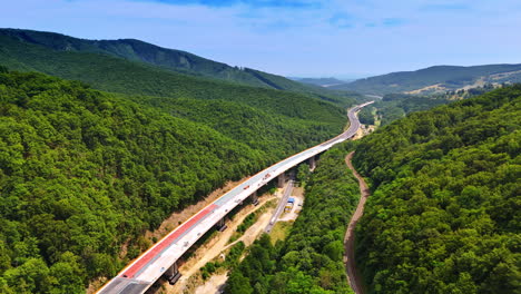 road winds through green mountains. a modern road winds through lush green mountains beneath a clear blue sky, blending nature and infrastructure