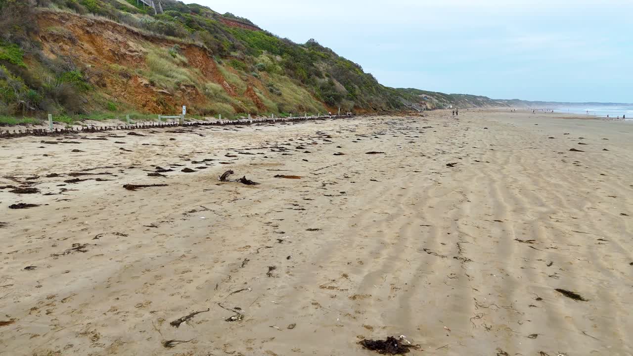 A tranquil beach scene with rippled sand and distant cliffs under soft daylight, captured at Ocean Grove, Victoria