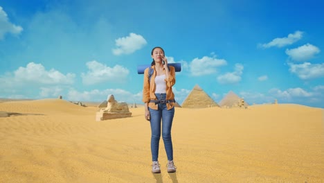 full body of asian female hiker with mountaineering backpack smiling and talking on smartphone while traveling in pyramid of giza
