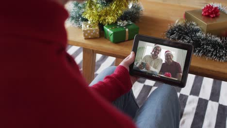 Hombre-Caucásico-Usando-Tableta-Para-Videollamada-Navideña,-Con-Familia-Sonriente-En-Pantalla