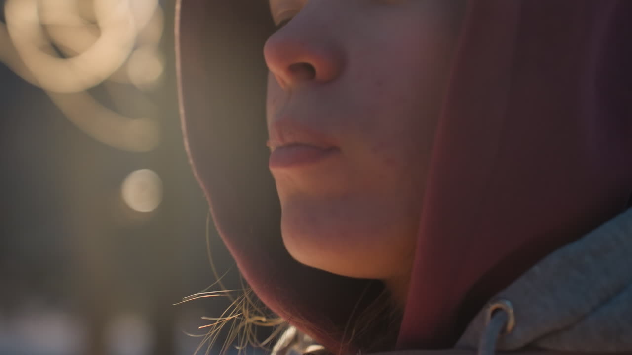 primer plano de una mujer disfrutando de un bocadillo al aire libre con luz cálida que se refleja en la cara, destacando la acogedora atmósfera de invierno, pastel crujiente dorado en la mano contrasta con el fondo fresco