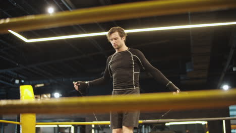 strict fit man using skipping rope in sport club. sport man warming up at gym