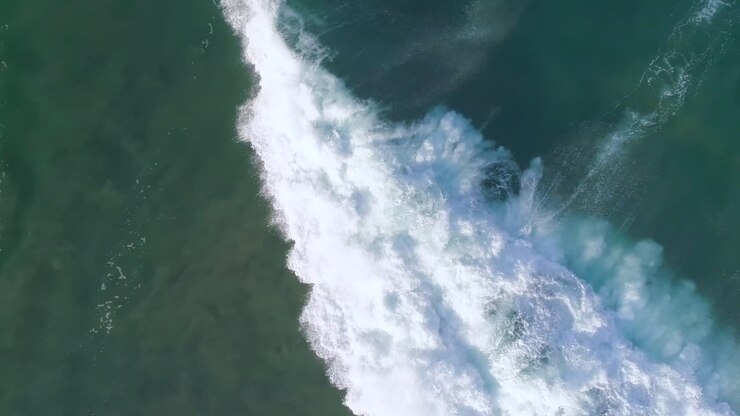 Aerial cenital cinematic shot of a surfer surfing a big tube barrel wave that creates a rainbow in Zicatela beach Puerto Escondido, Oaxaca