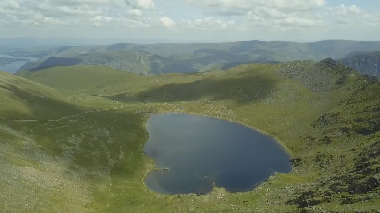 Droneoptagelser fra luften af bjerge og en sø i Lake District, England