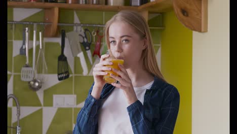 woman drinking orange juice in the kitchen