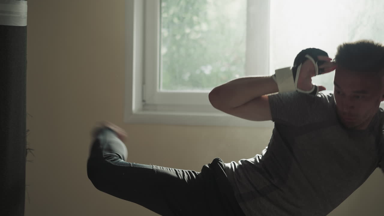 Man attacks punching bag training in sports club. Young sportsman kicks and punches heavy equipment with hands and leg in fighting gym slow motion. Strong fighter