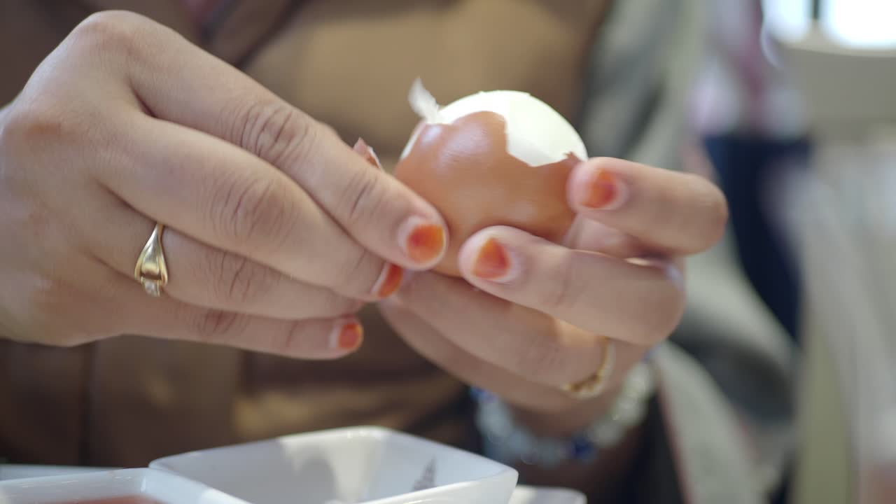 Close-up of hands peeling a hard-boiled egg