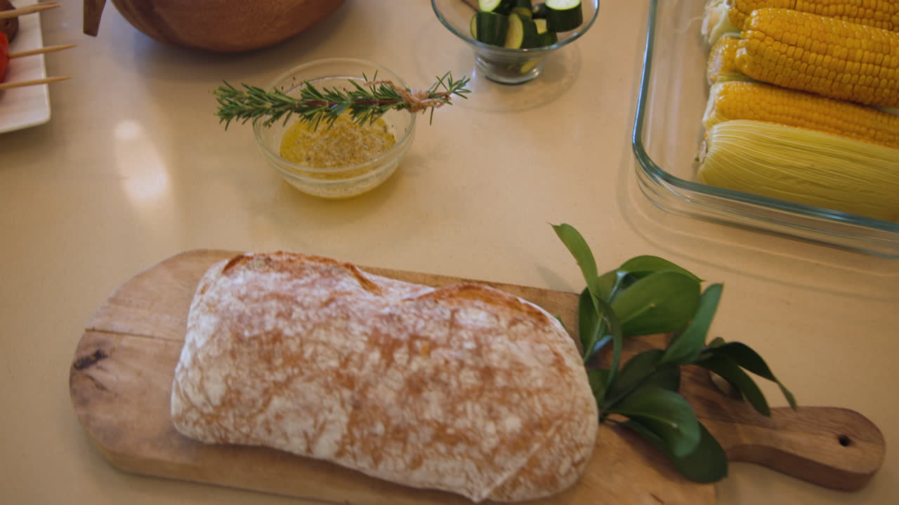 Fresh ciabatta bread on wooden board with herbs and butter, ready for serving, at home
