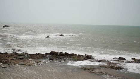 waves crash on a rocky shoreline under an overcast sky, creating a peaceful coastal scene
