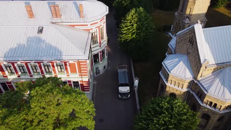 aerial view of garbage truck after loading waste automatically, shifting dumpster, early summer morning after the sunrise, green trees, wide angle birdseye drone shot moving backwards