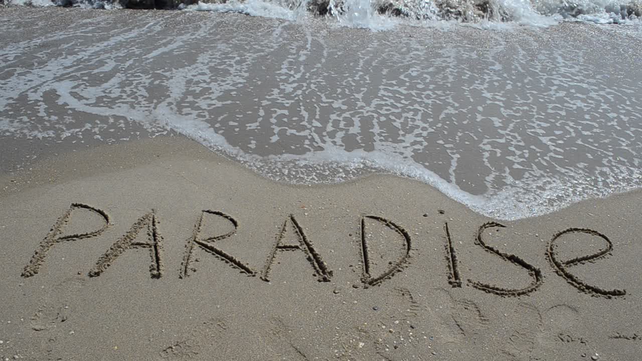 Iscrizione "Paradiso" nella sabbia su un'isola tropicale. Scatto sulla spiaggia