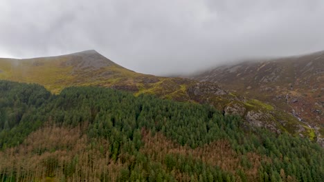 aerial hyperlapse of clouds covering the mountain peaks and pine forest in december winter snowdonia, wales