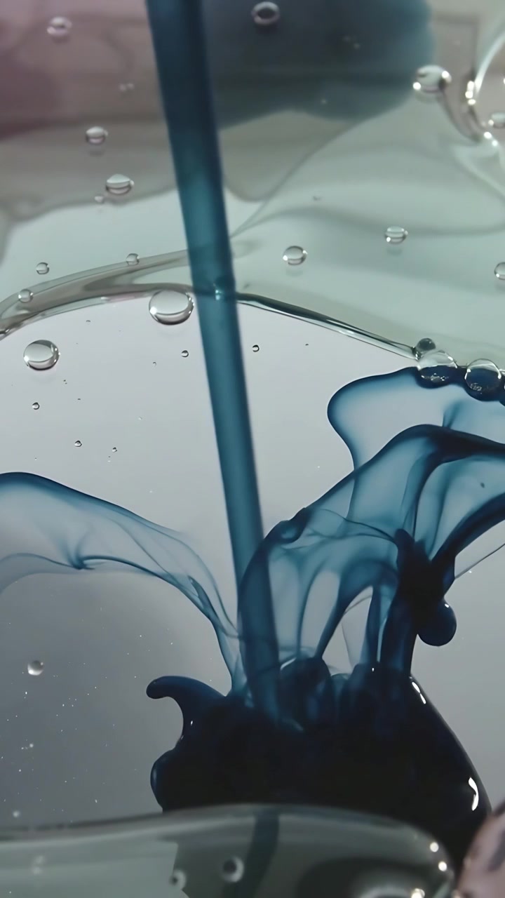 Vertical video: Detaching droplet from dropper forming blue plume in shallow dish, mixing