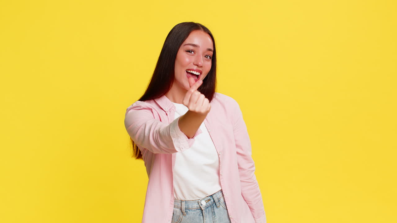 Woman smiling forming heart shape with fingers showing love kindness positive emotional gesture