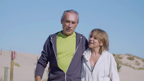 cheerful couple hugging and walking on background of mountains