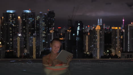 in pool on roof of a hotel in kuala lumpur malaysia woman working on a tablet